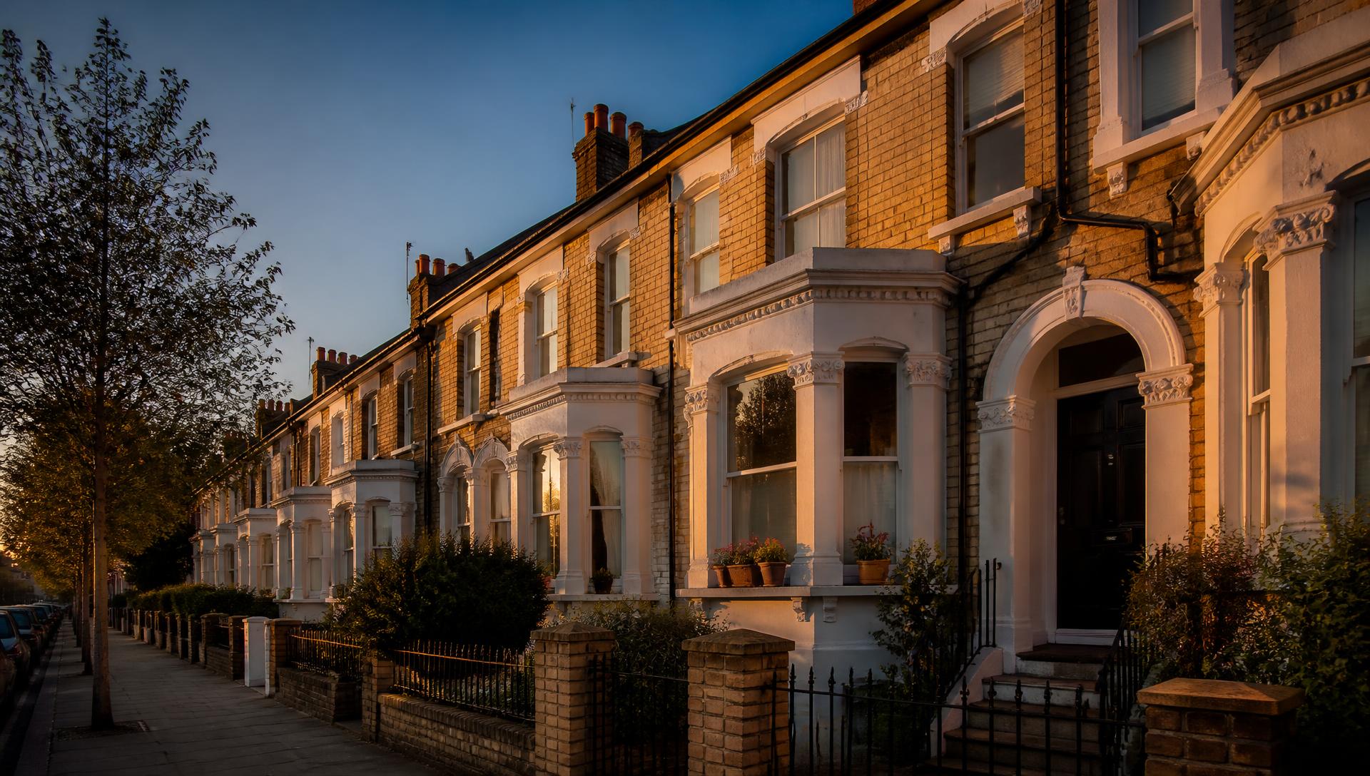 A row of British terraced houses lit by golden hour sunlight